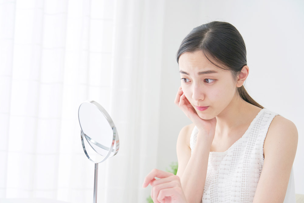鏡を見て悩む女性