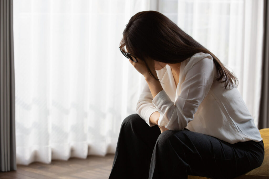 手を額にあててうつむいている女性