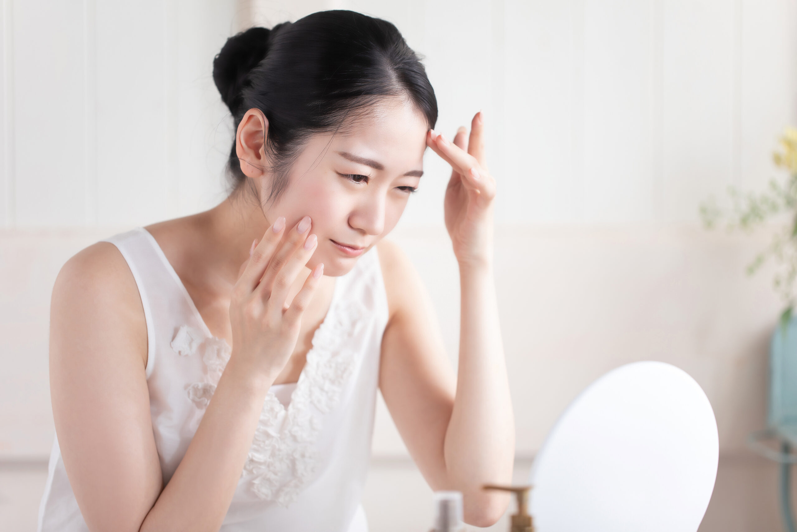 鏡の前で顔に手を添える女性